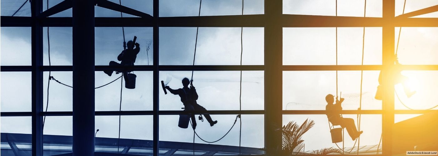 Geb&auml;udereiniger reinigen gro&szlig;e Fensterfronten in einer Flughafenhalle und sind im Bereich Facility Management t&auml;tig.