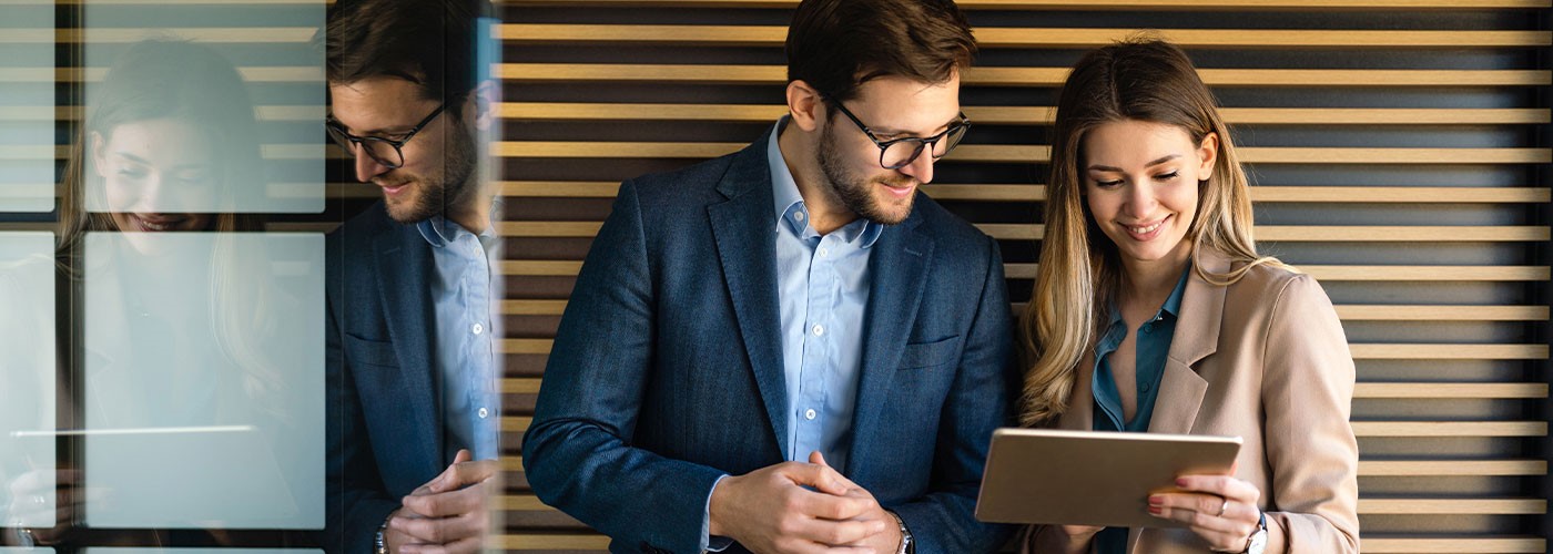 Das Bild zeigt eine junge Frau und einen jungen Mann in Business-Kleidung.