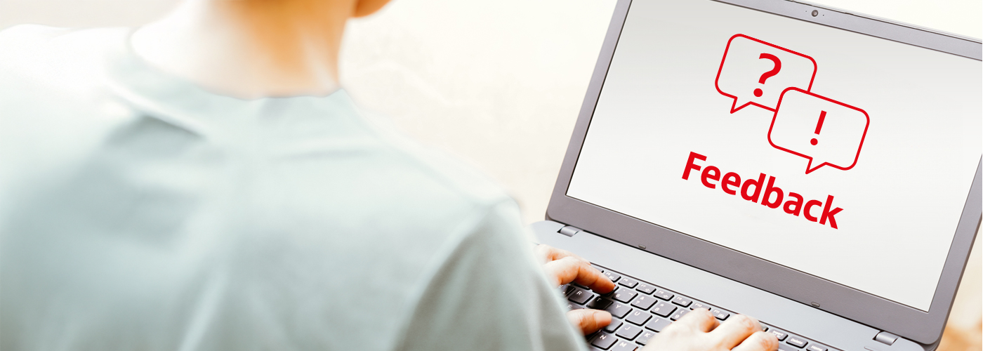 Eine Person sitzt mit dem Rücken zum Betrachter an einem Laptop. Auf dem Bildschirm ist ein Piktogramm in roter Farbe mit dem Text Feedback zu sehen.