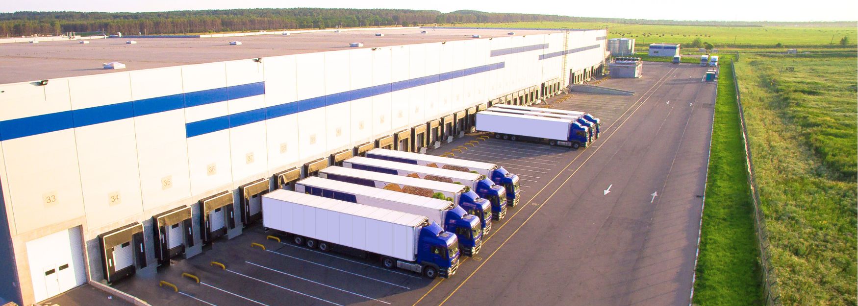 A freight forwarding and logistics company operates a large warehouse, in front of which numerous trucks are parked while loading and unloading goods.