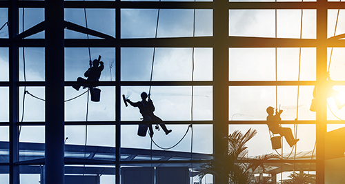 Geb&auml;udereiniger reinigen gro&szlig;e Fensterfronten in einer Flughafenhalle.