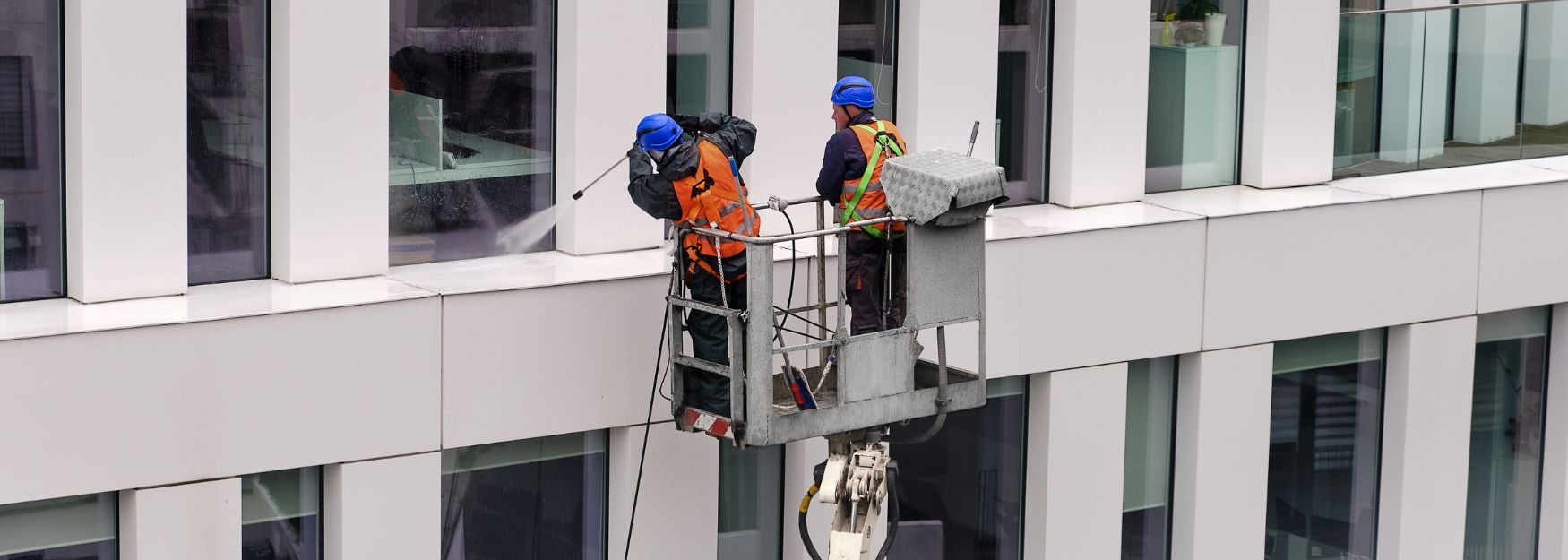 Gebäudereiniger reinigen Fensterfronten von außen an einem Gebäude. un