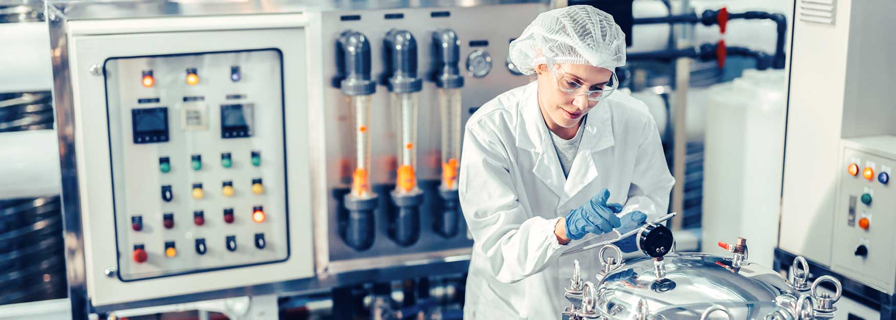 Eine Mitarbeiterin bedient eine Maschine in der Chemieindustrie.